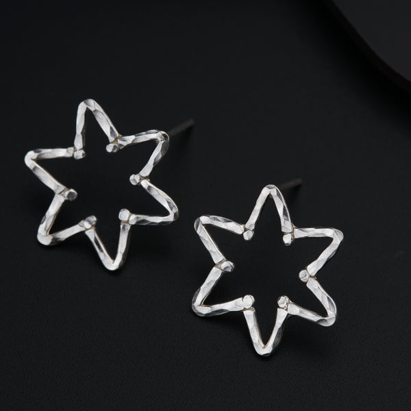 a pair of star shaped earrings sitting on top of a table