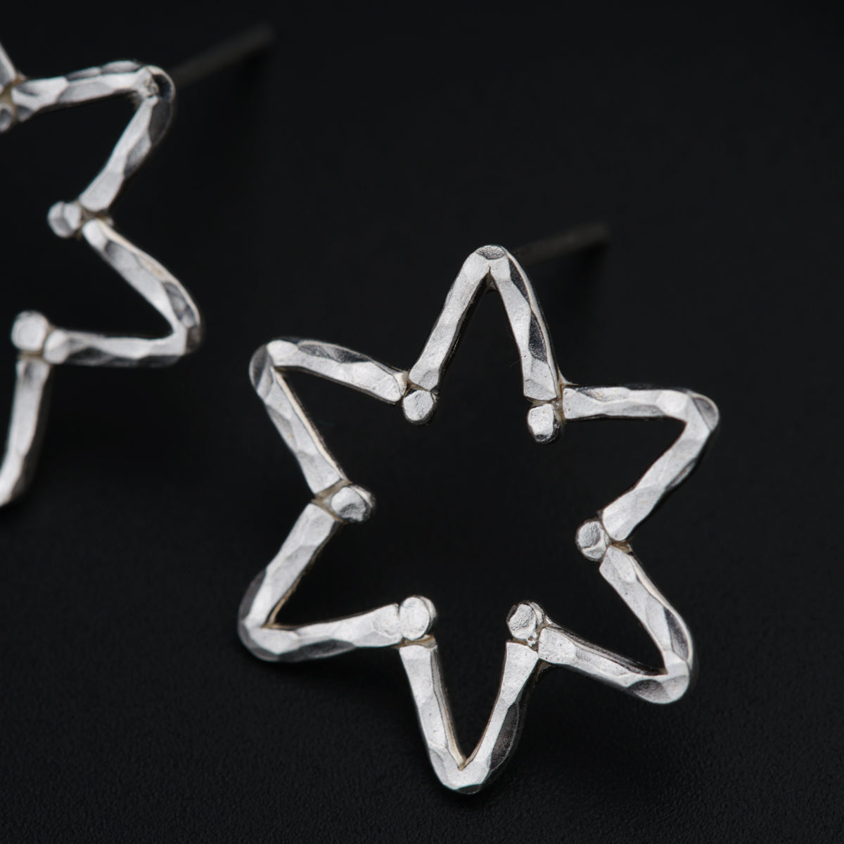 a pair of star shaped earrings on a black surface