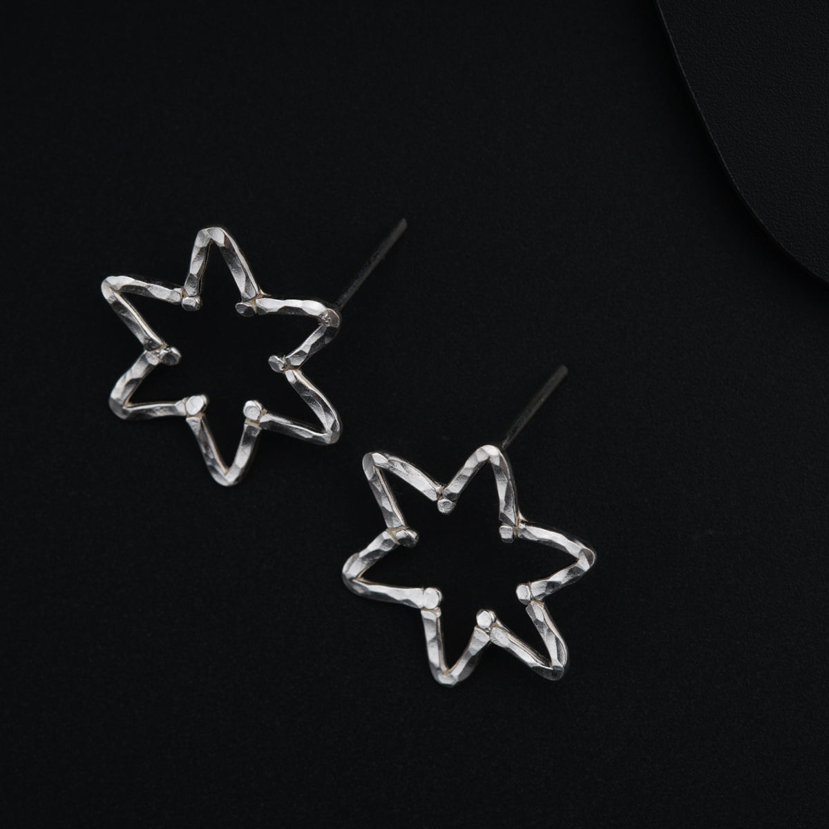 a pair of star shaped earrings on a black surface