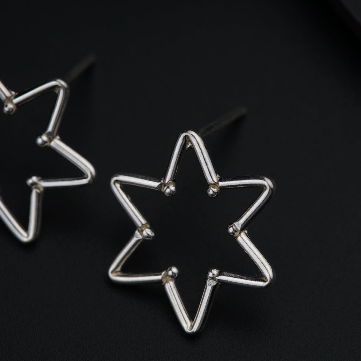 a pair of star shaped earrings on a black surface