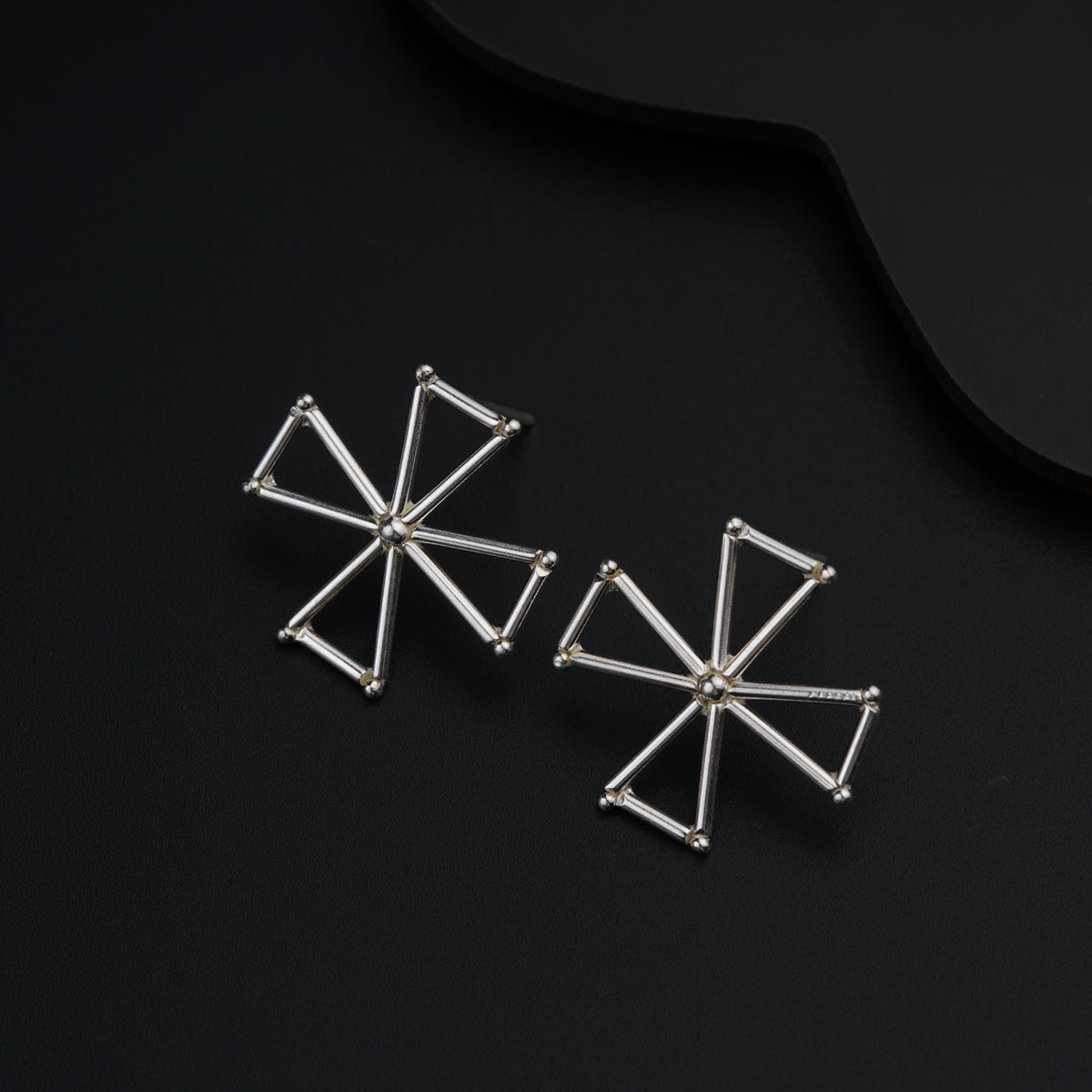 a pair of earrings sitting on top of a black surface