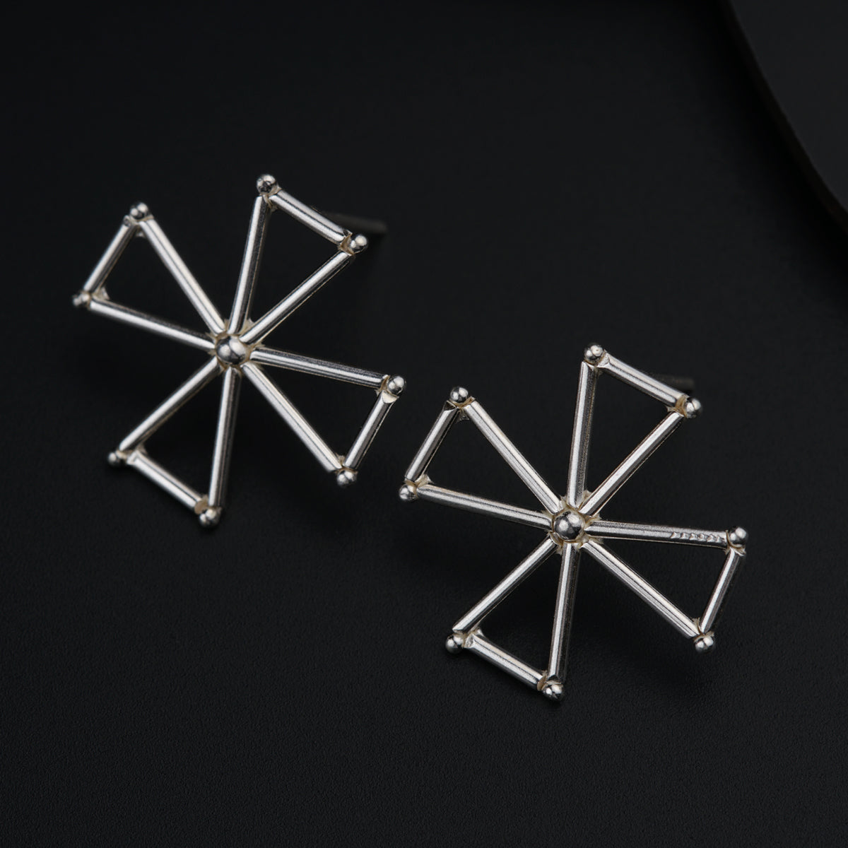 a pair of silver earrings on a black surface