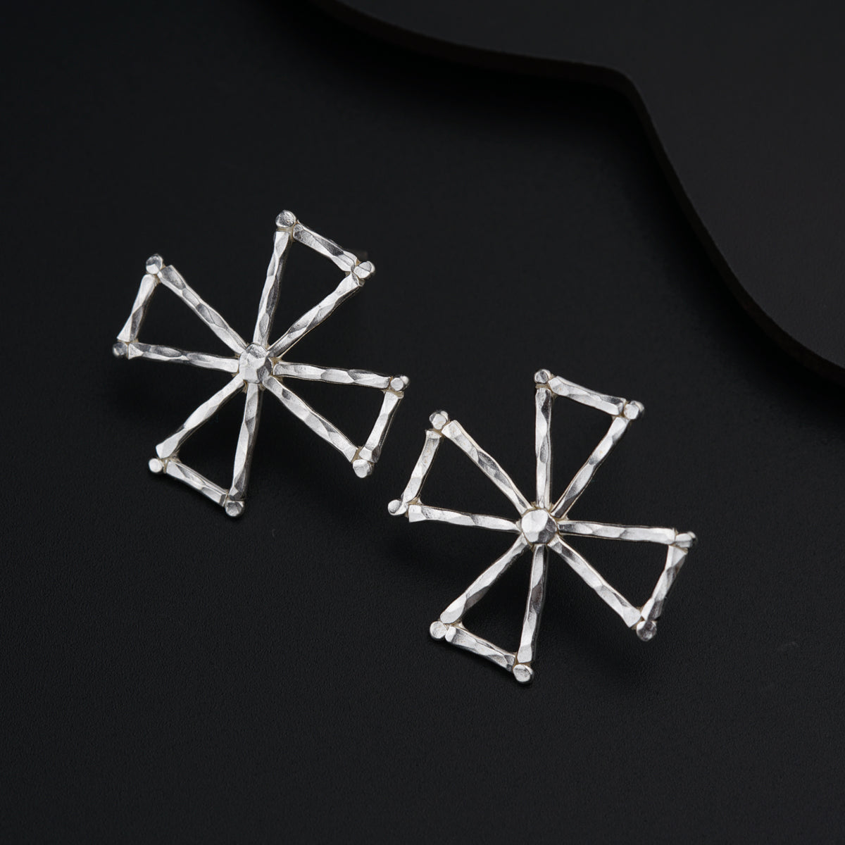 a pair of earrings sitting on top of a black surface