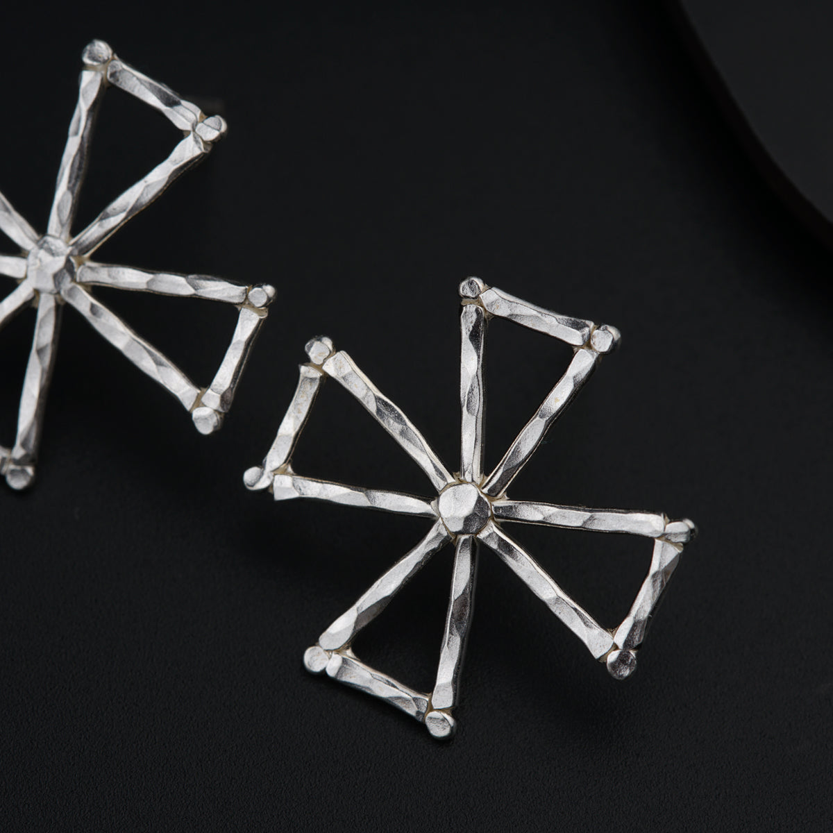 a pair of silver earrings sitting on top of a black surface