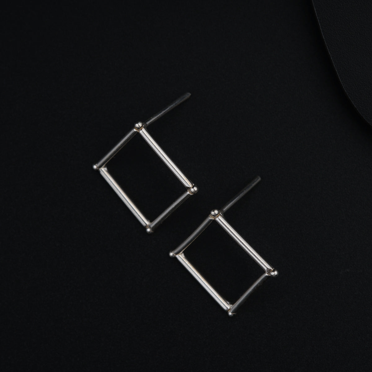 a pair of earrings sitting on top of a black surface