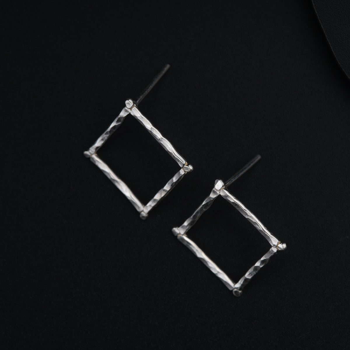 a pair of square shaped earrings on a black surface