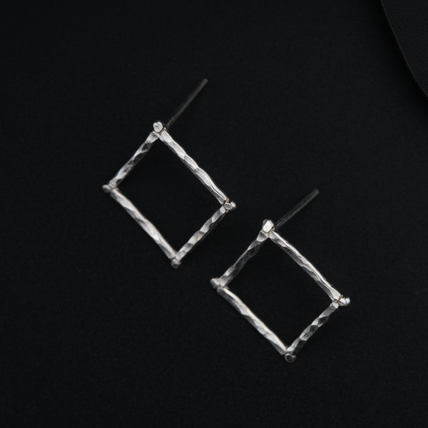 a pair of square shaped earrings on a black surface