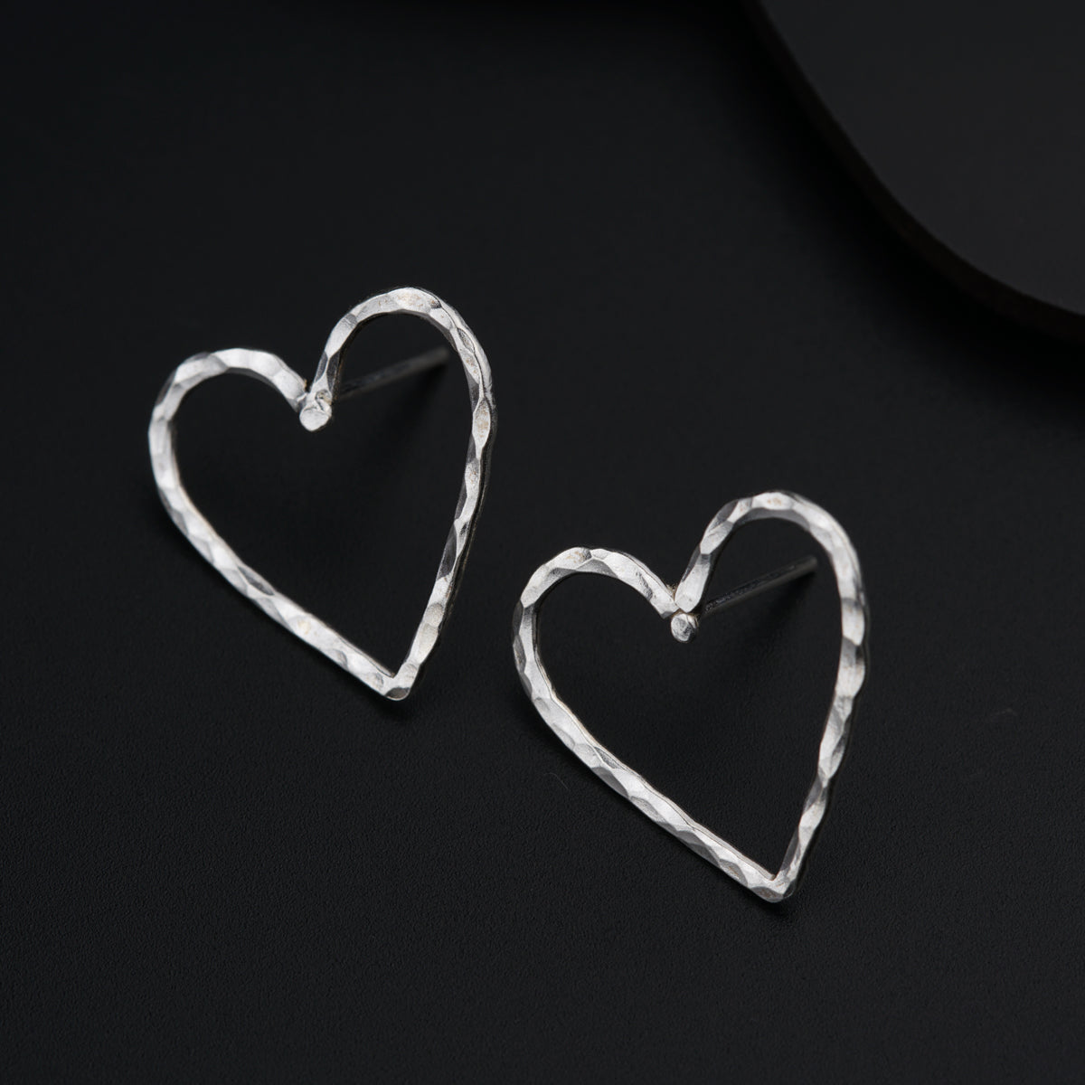 a pair of heart shaped earrings sitting on top of a table