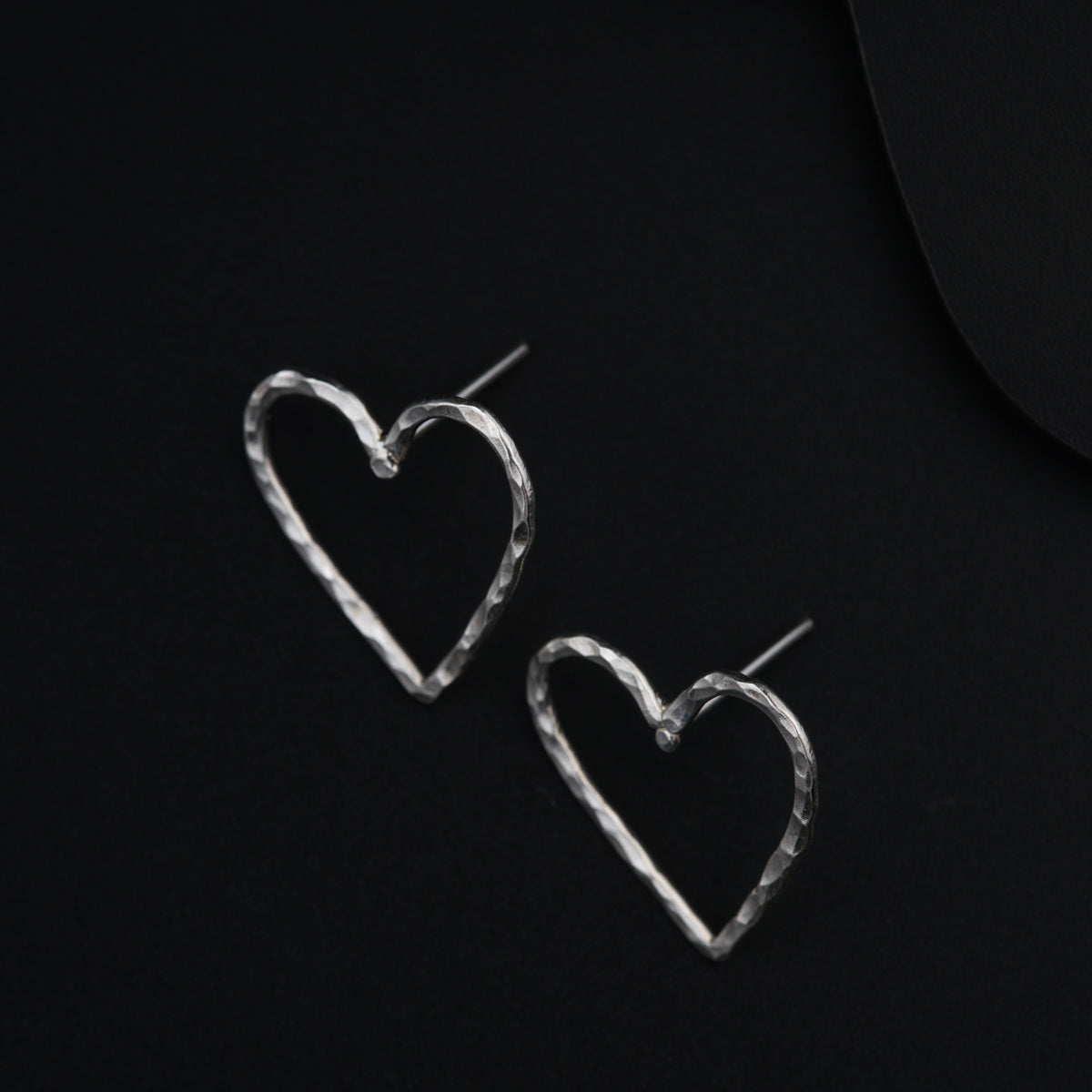 a pair of heart shaped earrings on a black background