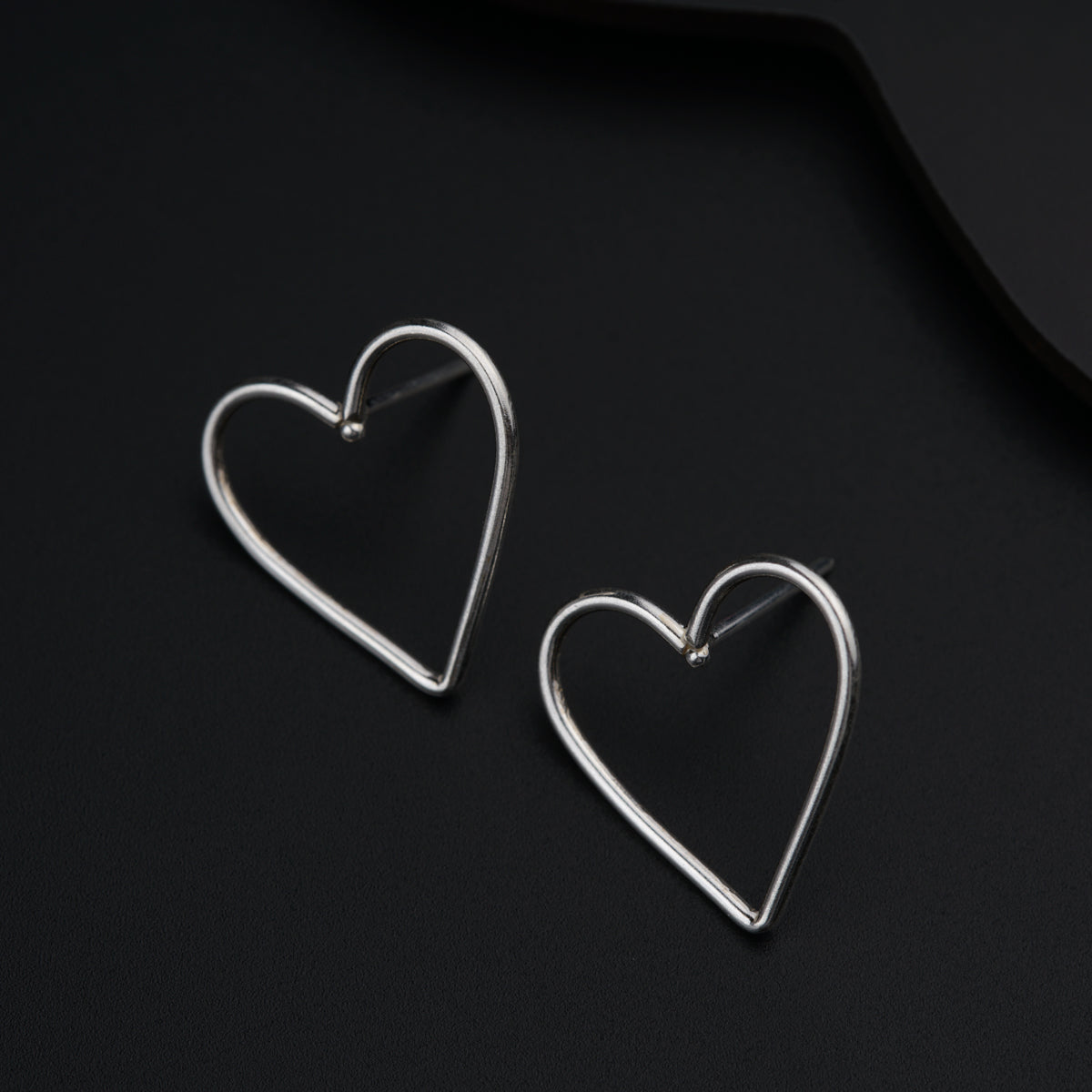 a pair of heart shaped earrings sitting on top of a table