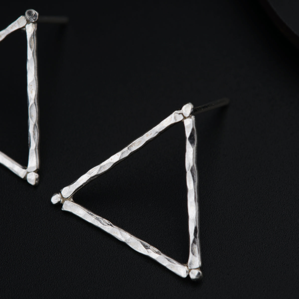 a pair of silver earrings on a black surface