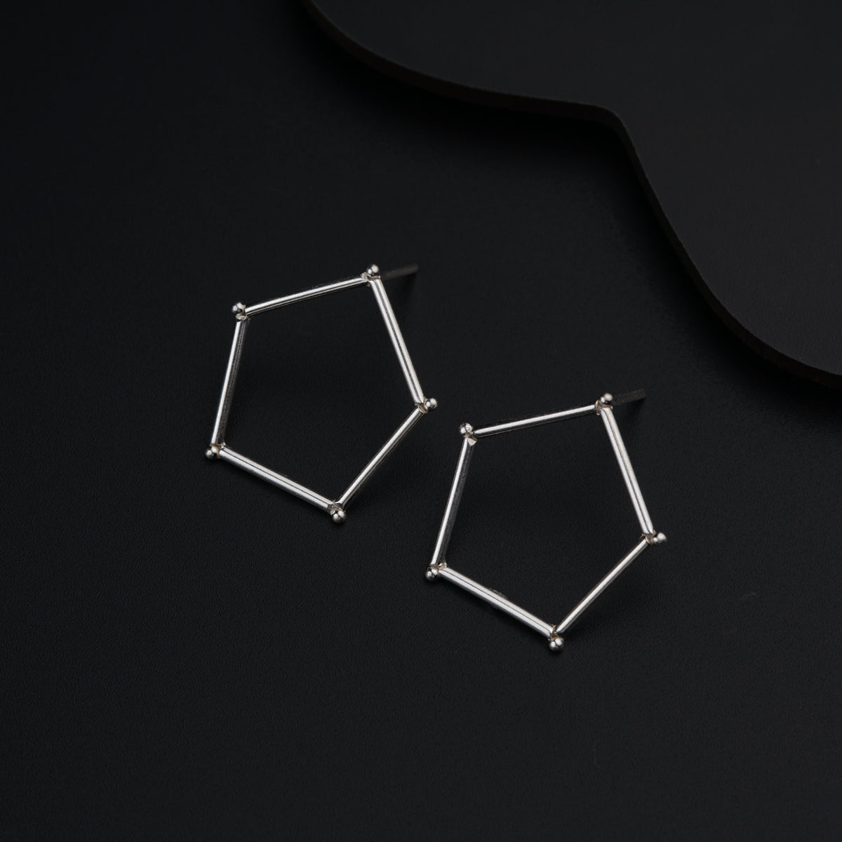 a pair of earrings sitting on top of a black surface