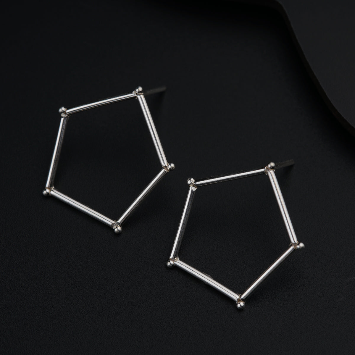 a pair of silver earrings on a black surface