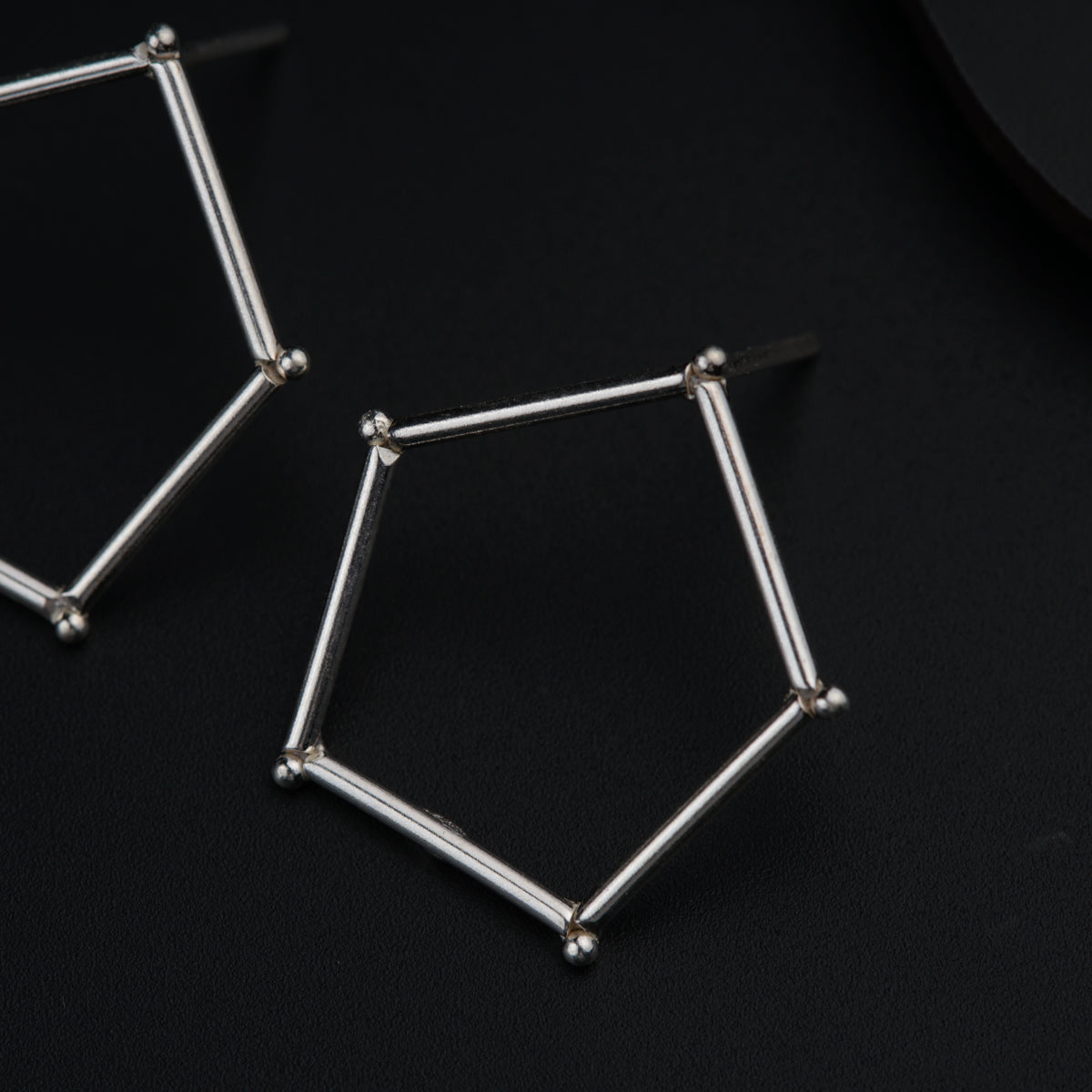 a pair of silver earrings sitting on top of a black surface
