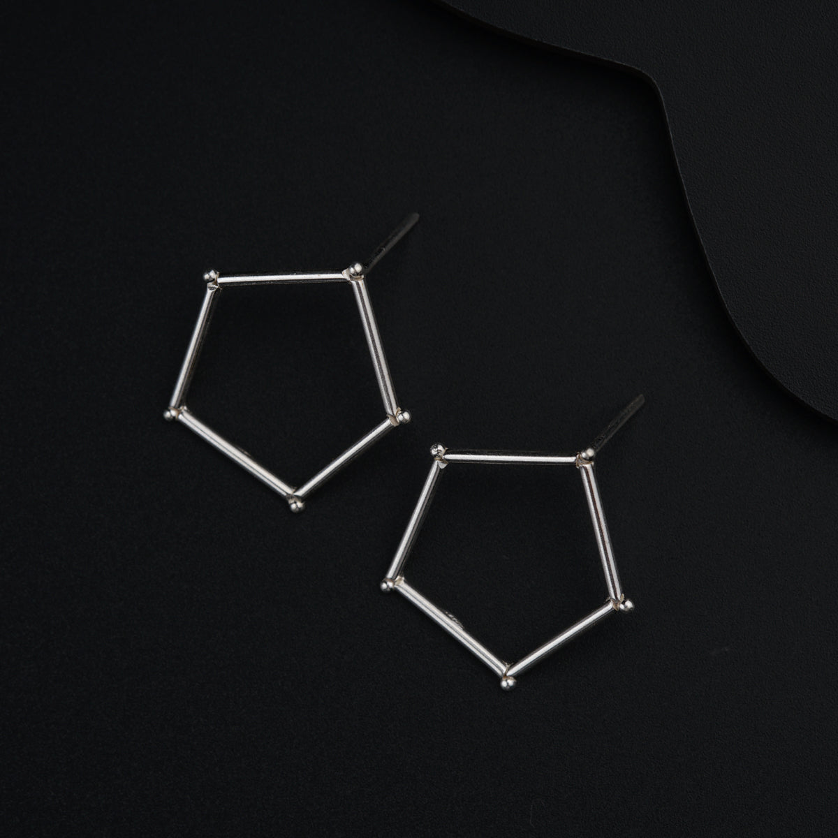 a pair of silver earrings sitting on top of a black surface