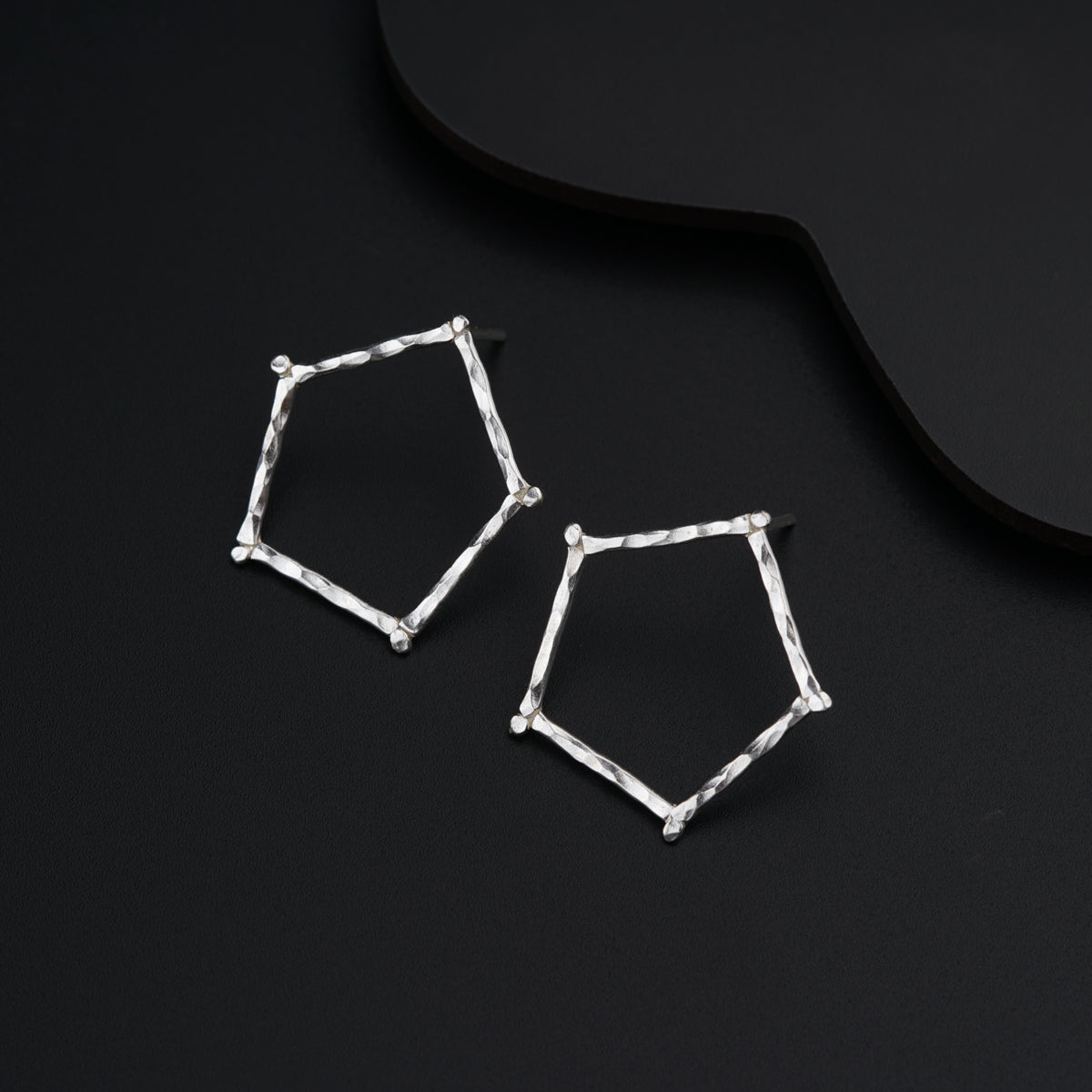 a pair of silver earrings sitting on top of a black surface