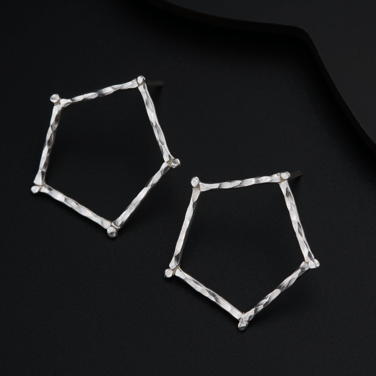 a pair of silver earrings sitting on top of a black surface