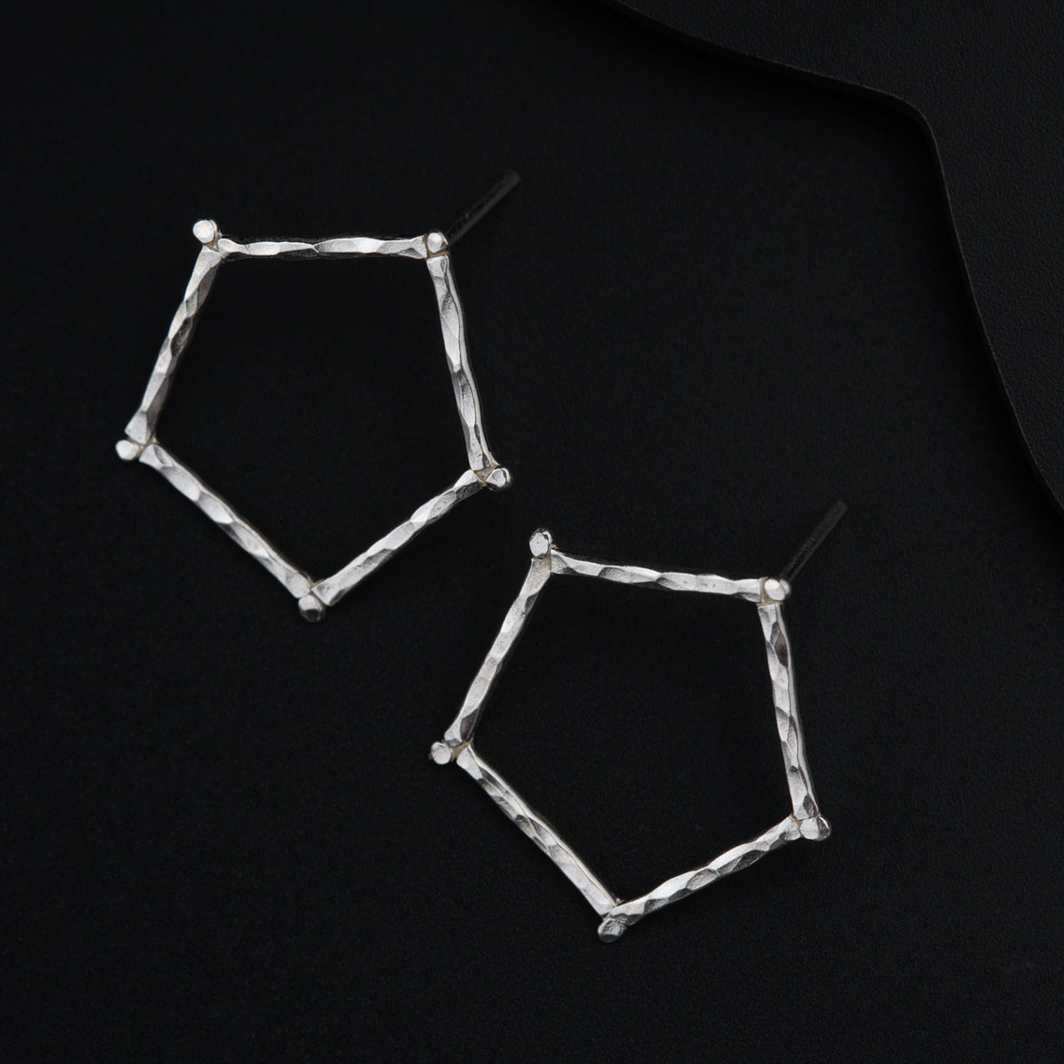 a pair of silver earrings on a black surface