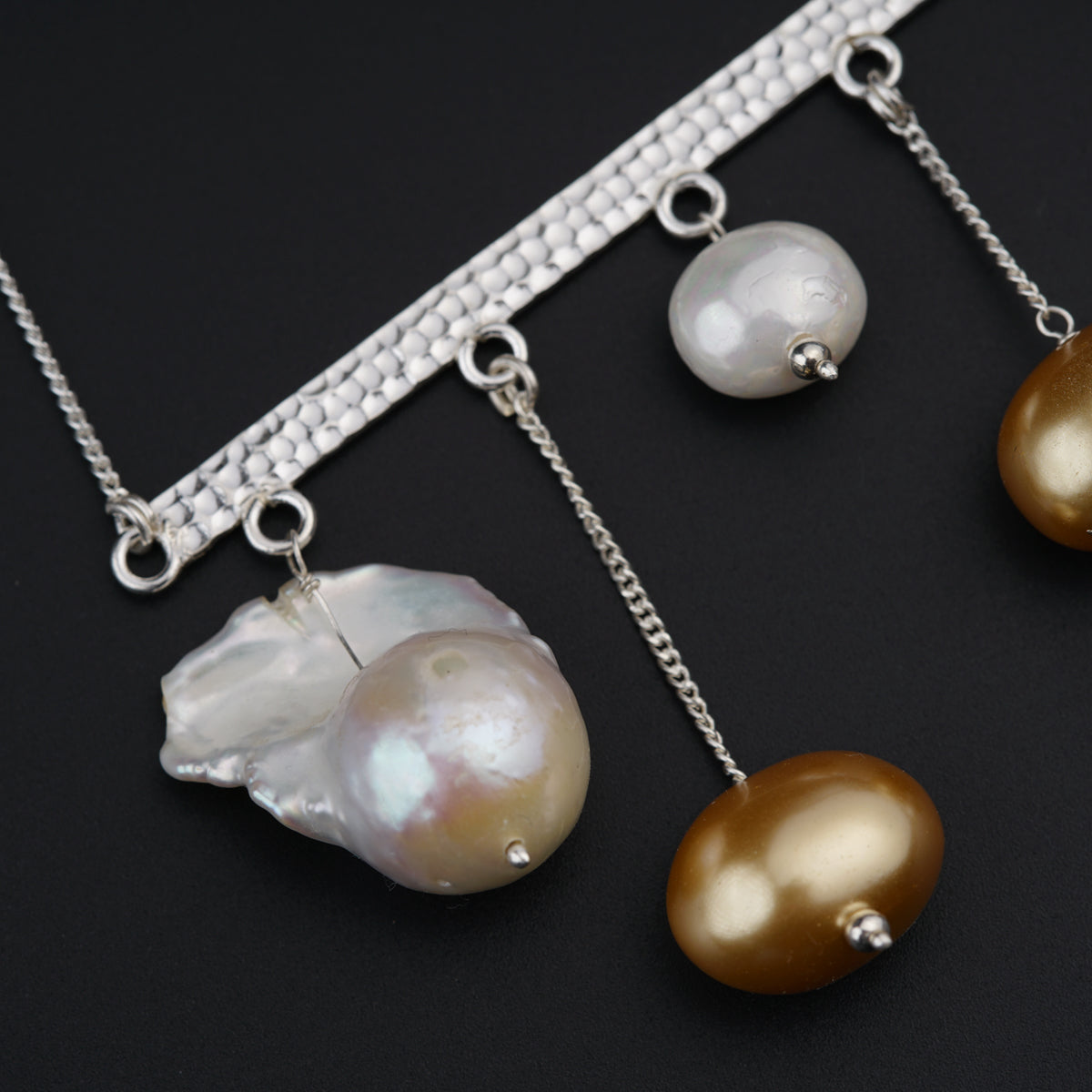 a close up of three necklaces on a black surface