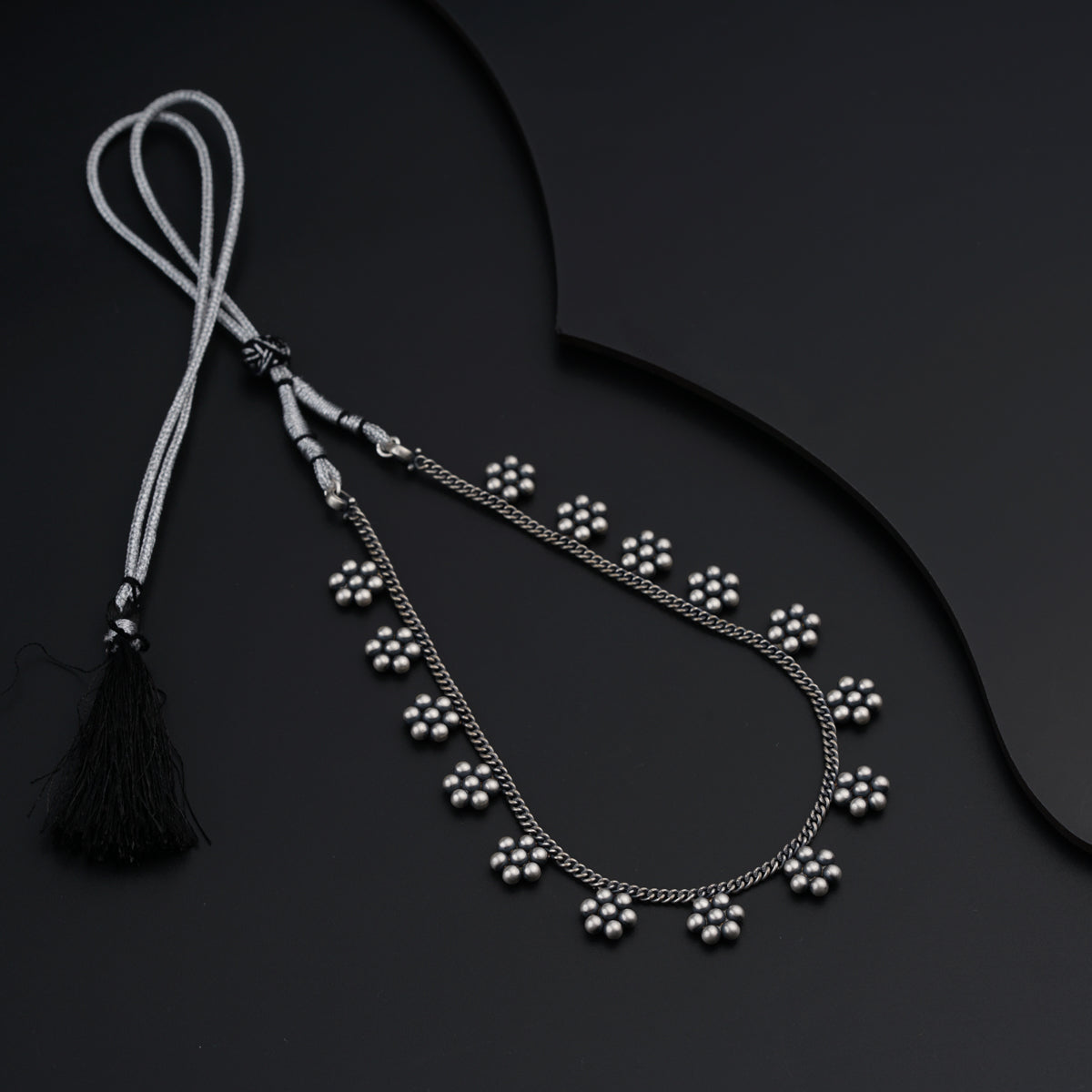 a black and white photo of a tasseled necklace