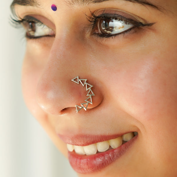 Close-up of a woman's face with silver geometric nose ring and eye makeup