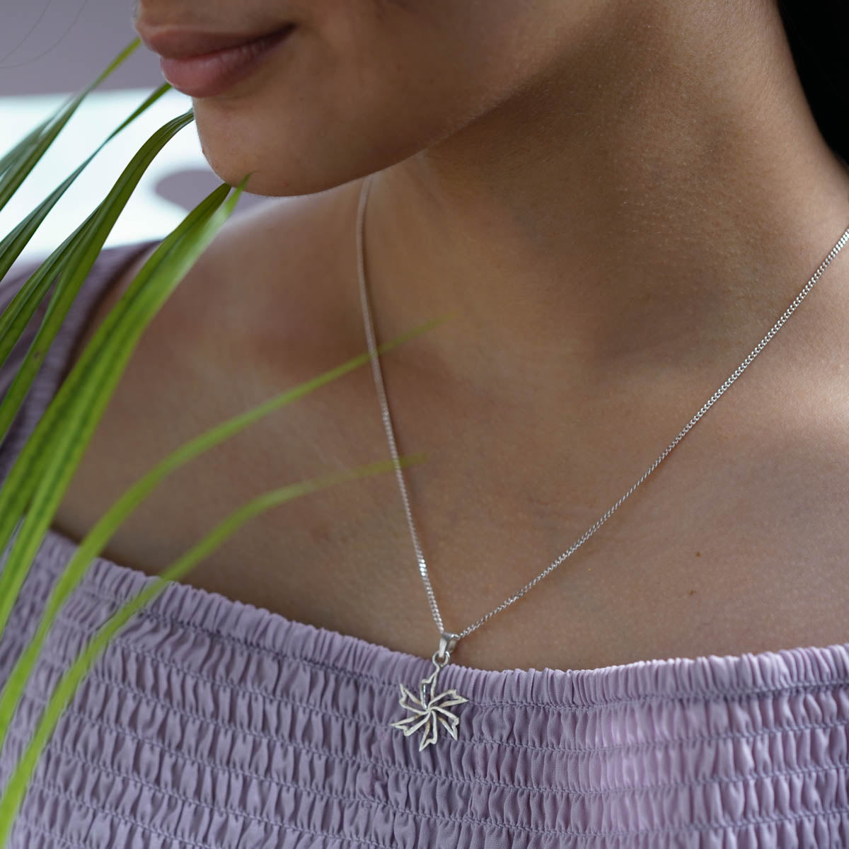 a woman wearing a necklace with a flower on it