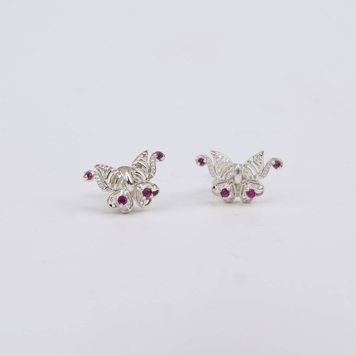 Silver butterfly earrings with pink stones on white background