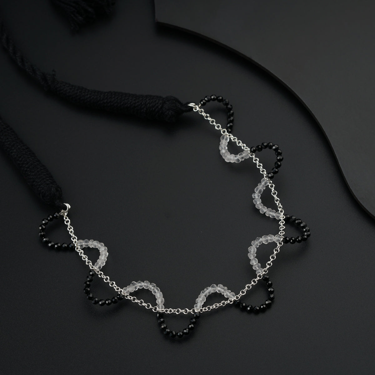 a black and white necklace on a black surface