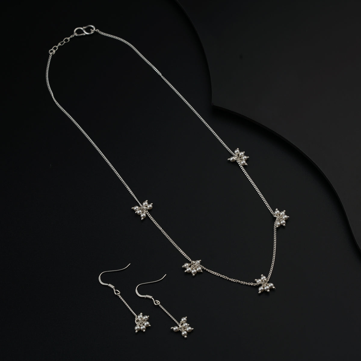 a necklace and earrings on a black surface