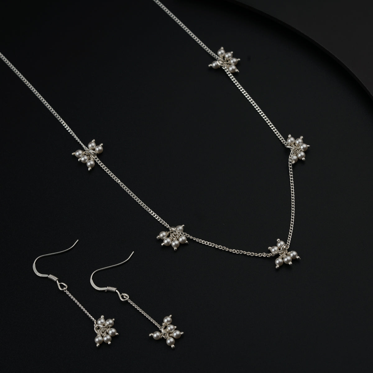 a necklace and earrings on a black surface