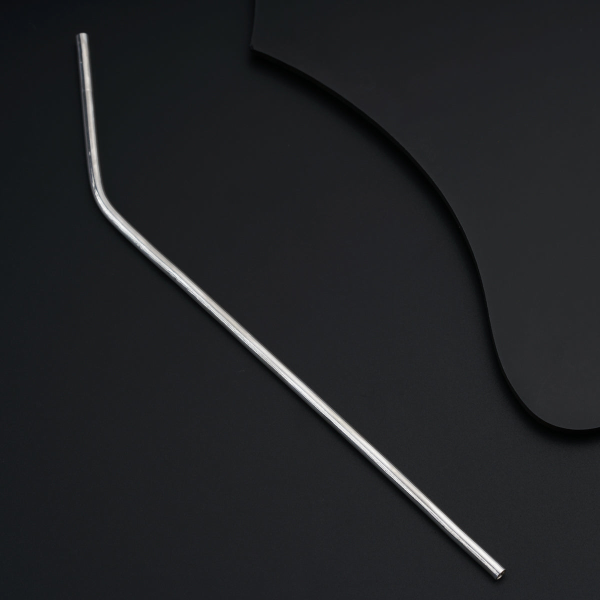 a pair of metal straws sitting on top of a black surface