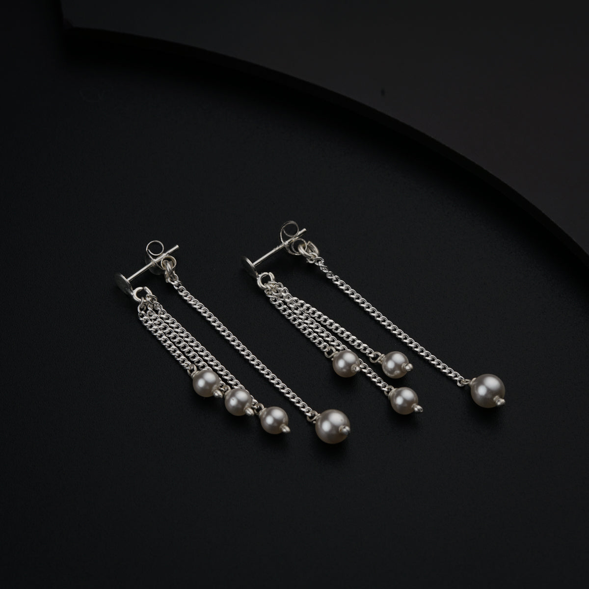 three pairs of dangling earrings on a black surface