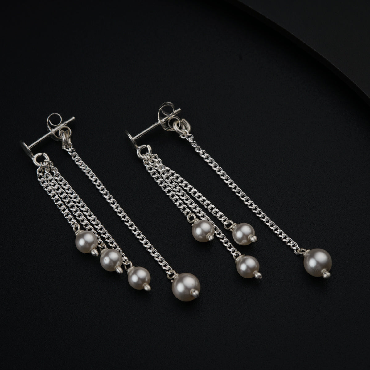 a pair of earrings with pearls hanging from them