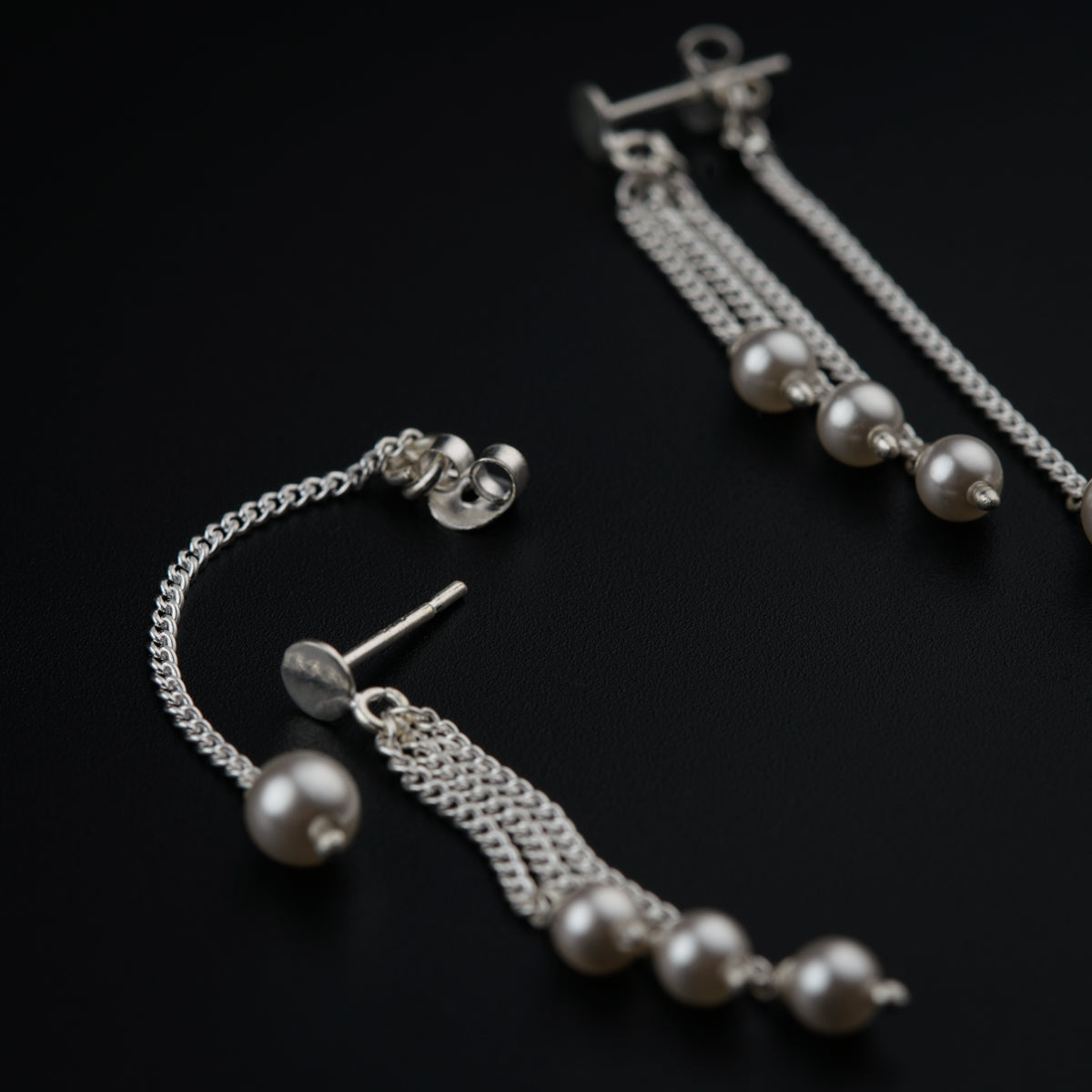 a pair of earrings with pearls hanging from them