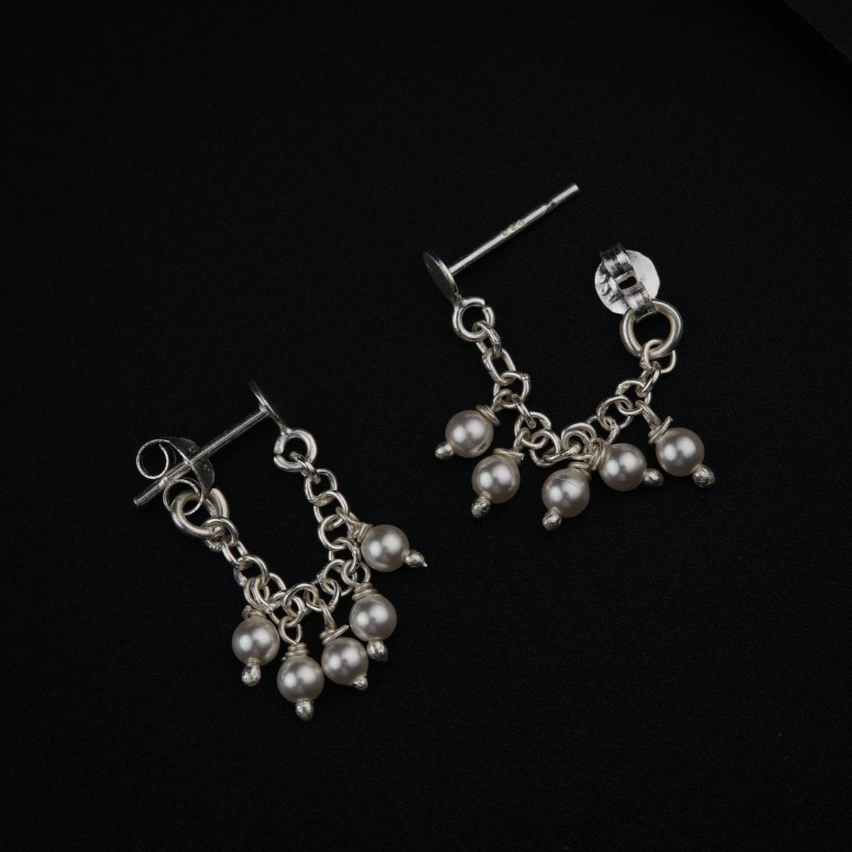 a pair of earrings with pearls hanging from them