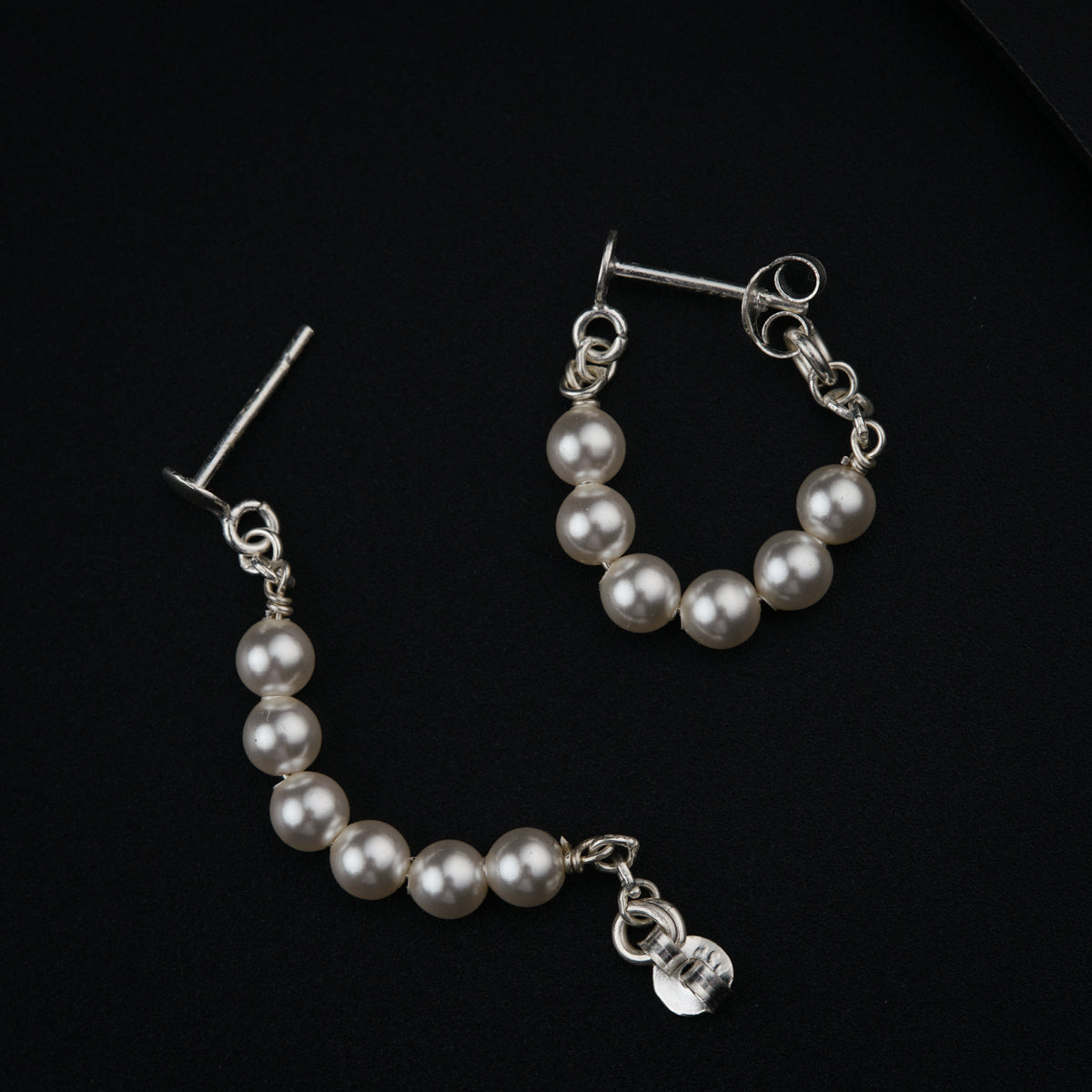 a pair of earrings with pearls on a black background