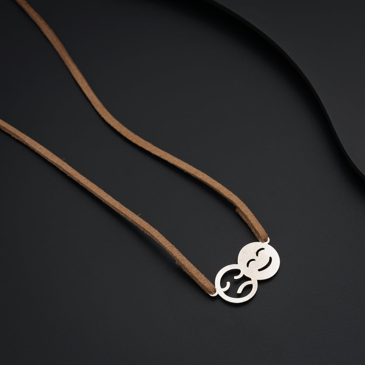 a necklace with a smiley face on a brown cord