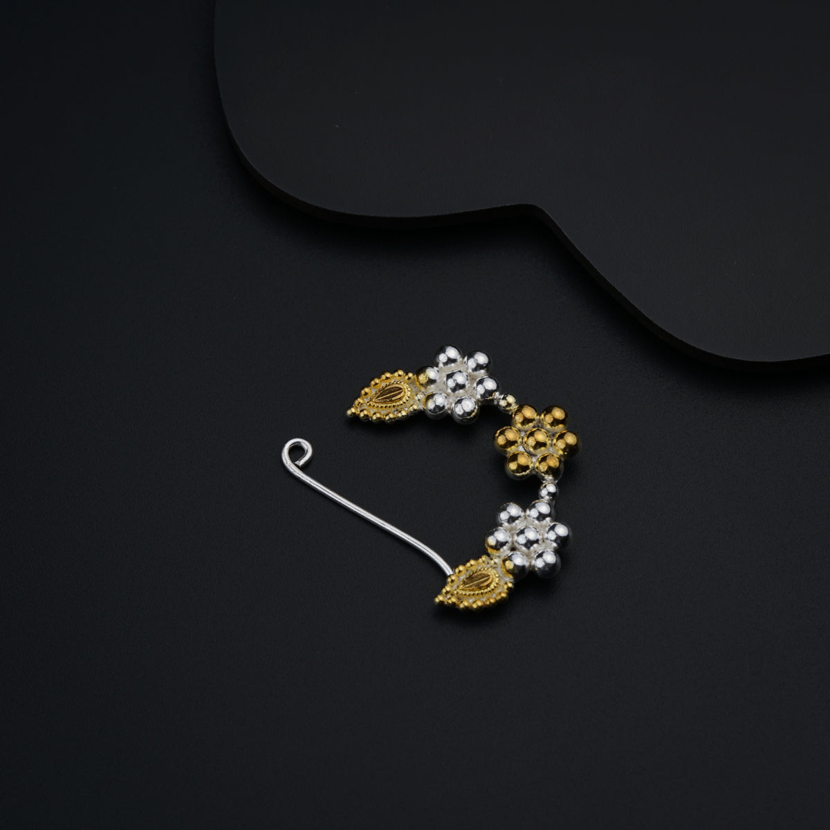 a pair of gold and white earrings on a black background
