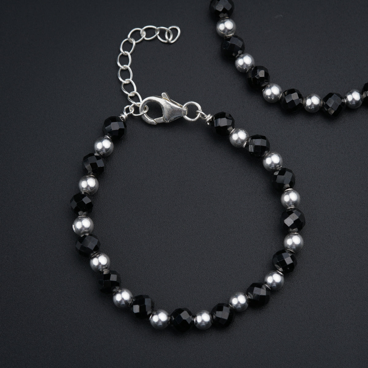 a black and silver beaded bracelet on a black surface