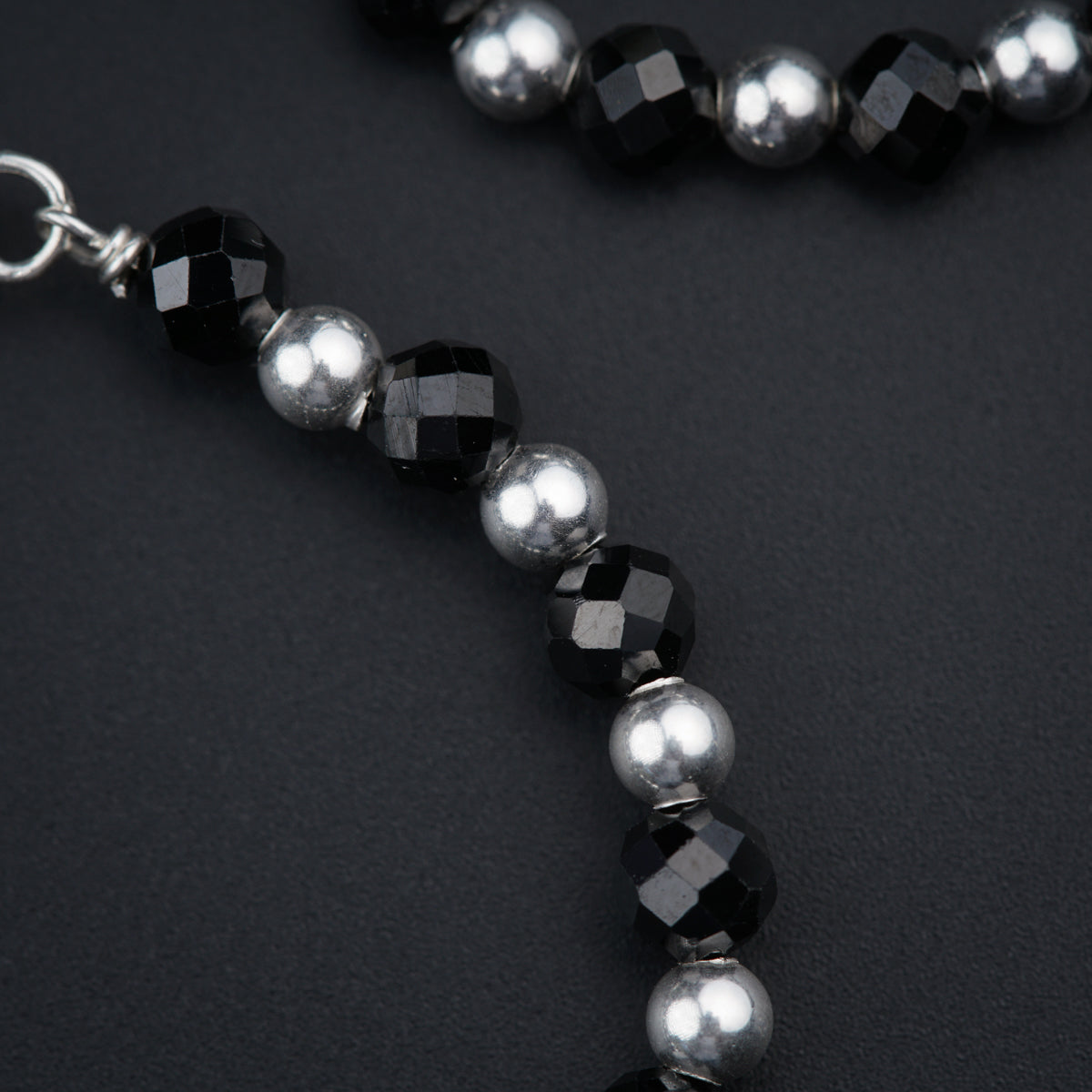 a black and silver beaded necklace on a black surface