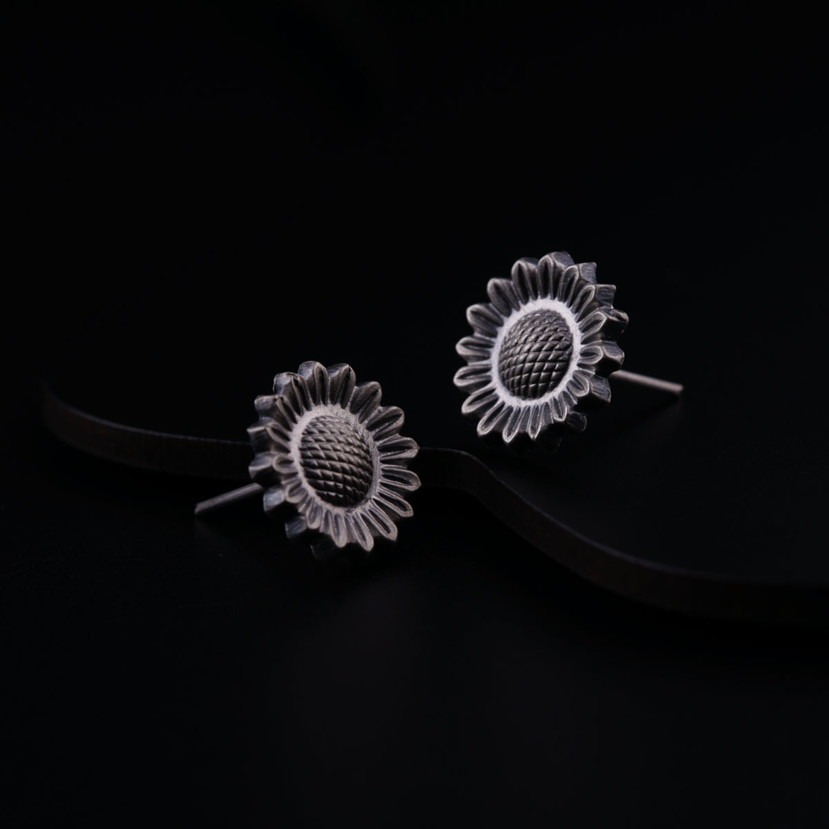 a pair of sunflower earrings on a black background