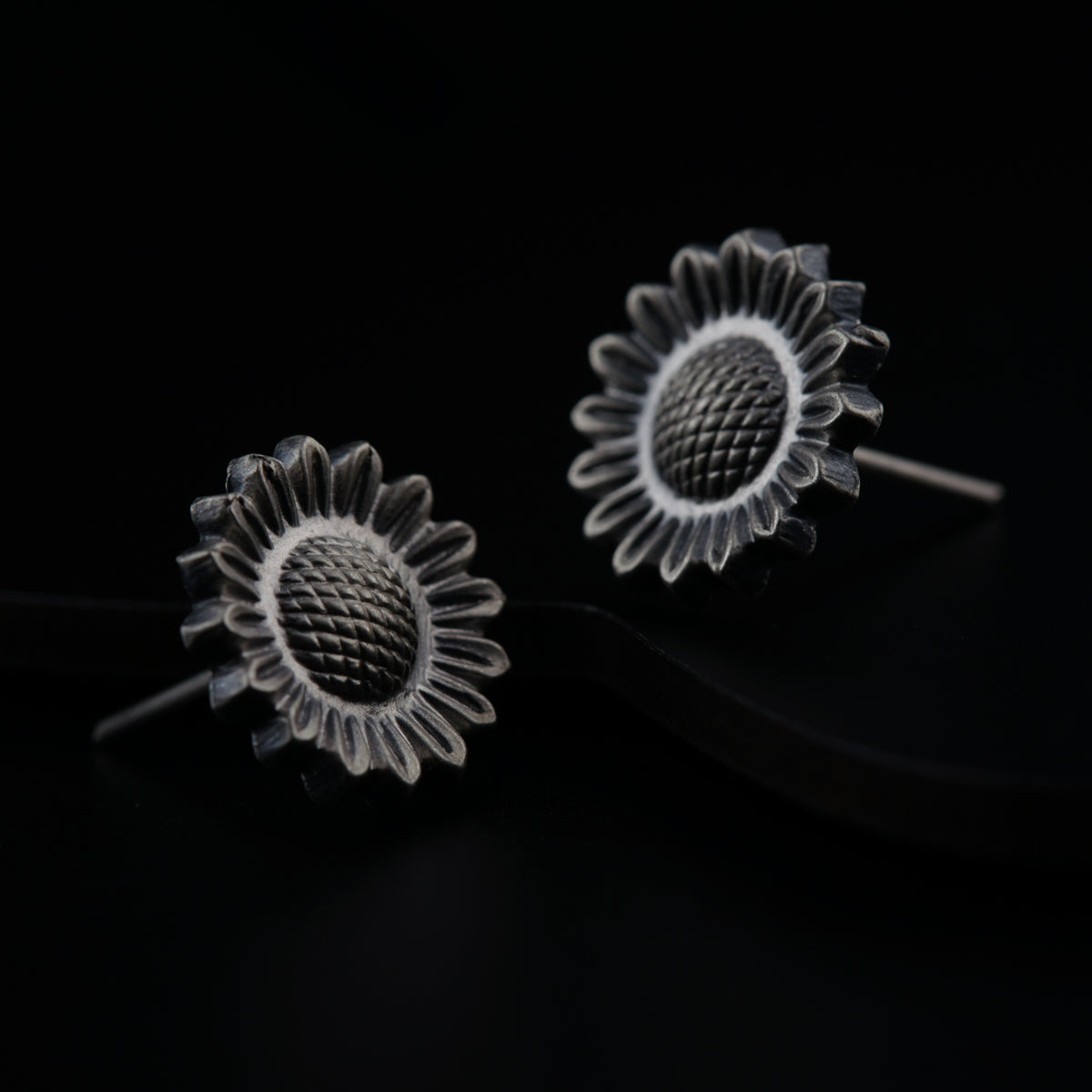 a pair of sunflower earrings on a black background