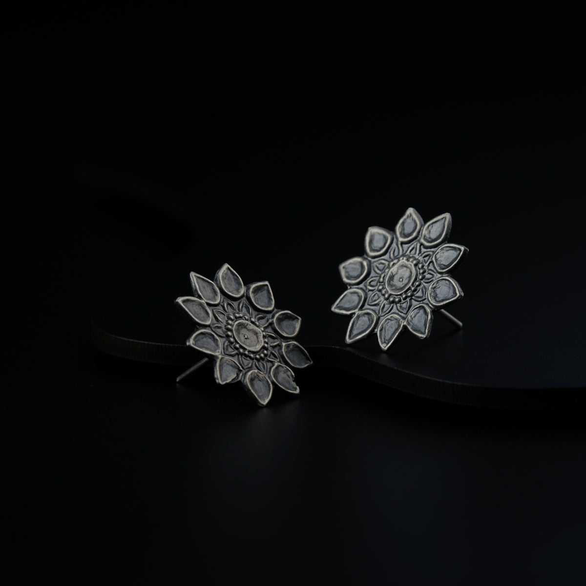 a pair of silver earrings on a black background