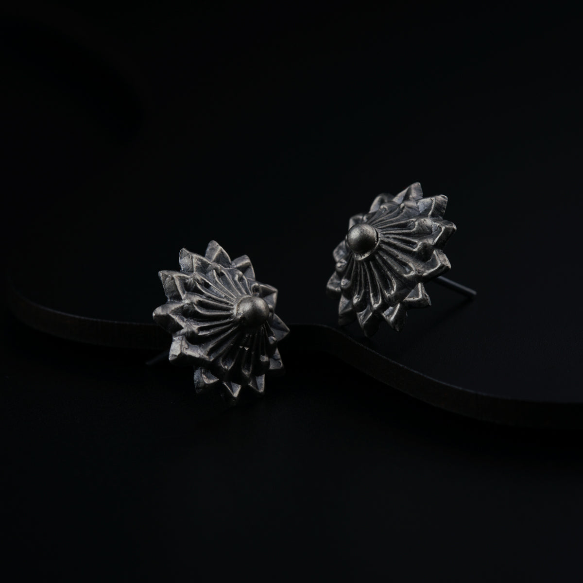 a pair of silver earrings sitting on top of a black surface