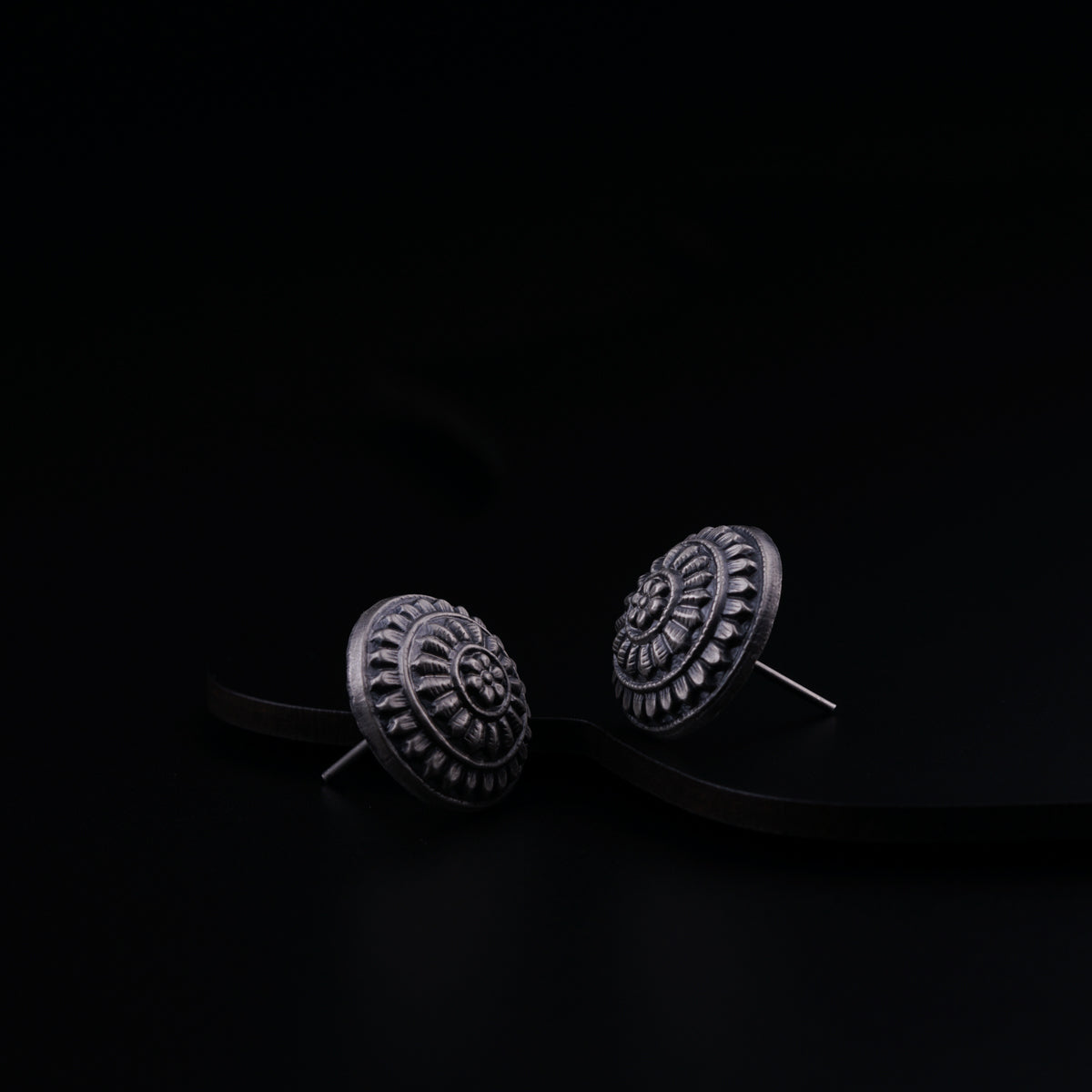 a pair of earrings sitting on top of a black surface