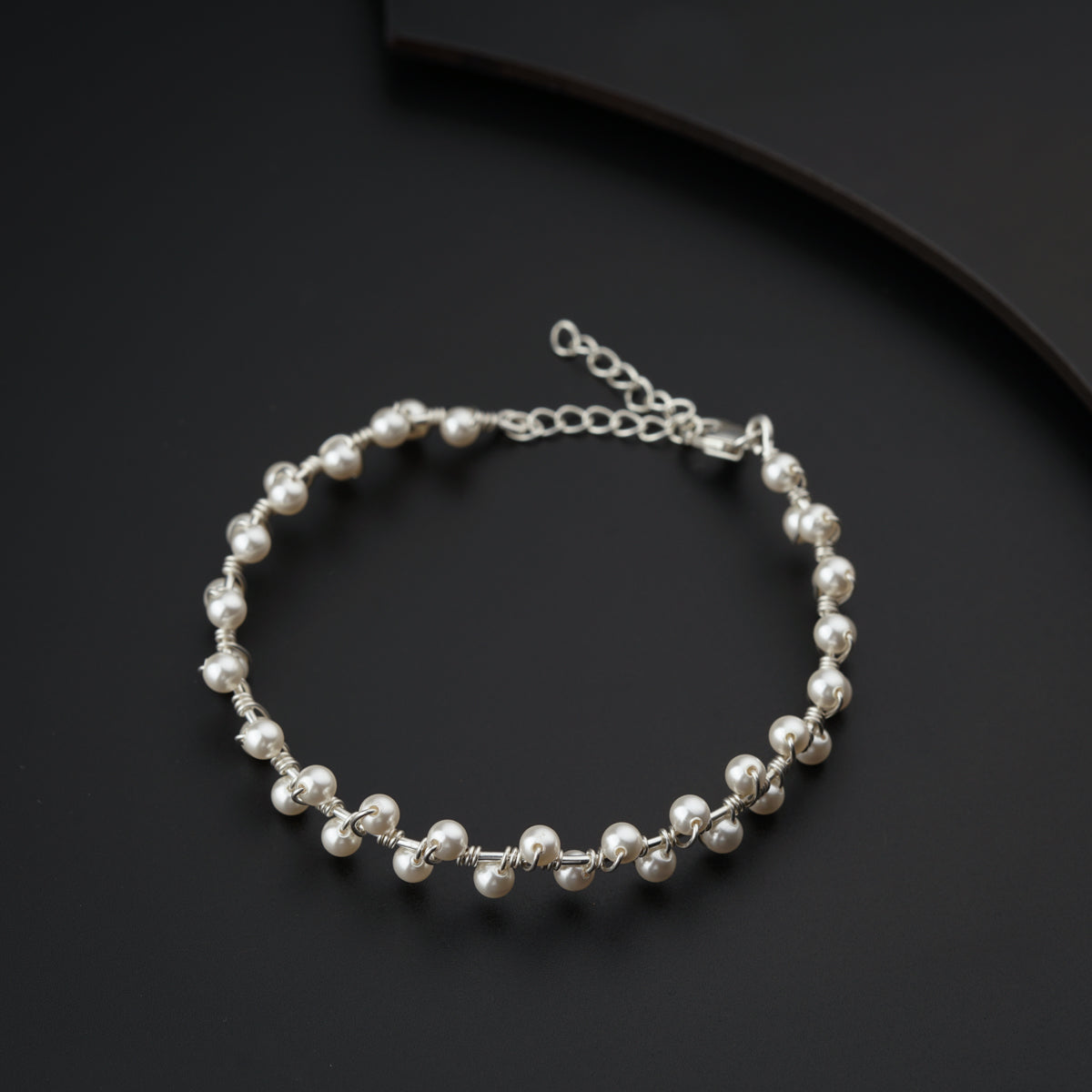 a bracelet with pearls on a black surface