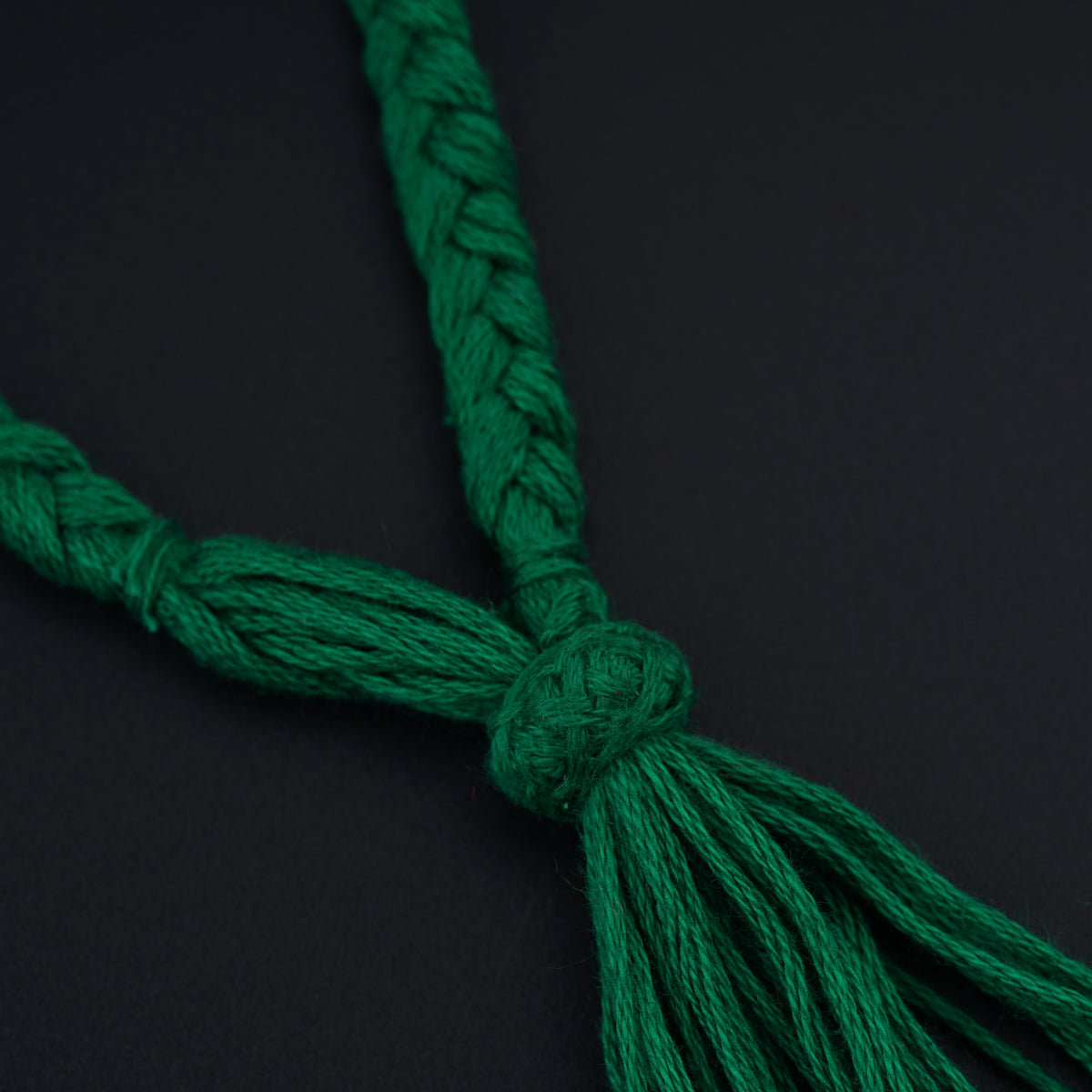 a close up of a green tassel on a black surface