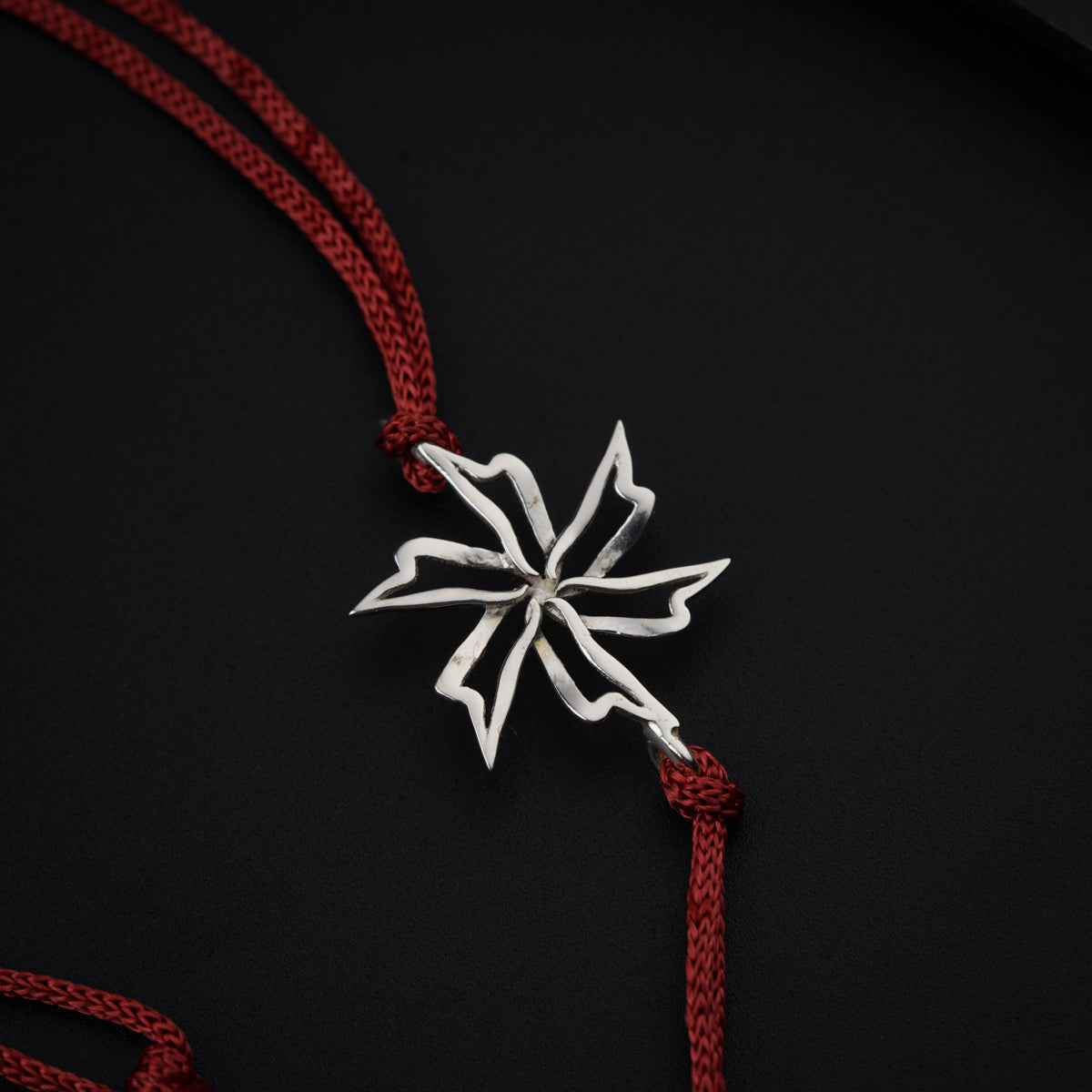 a silver snowflake on a red string