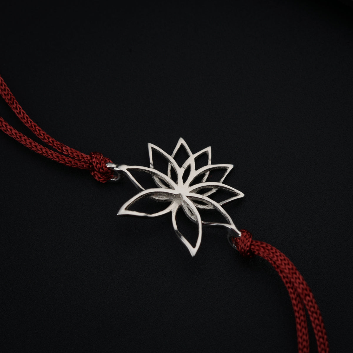 a white flower on a red string on a black background