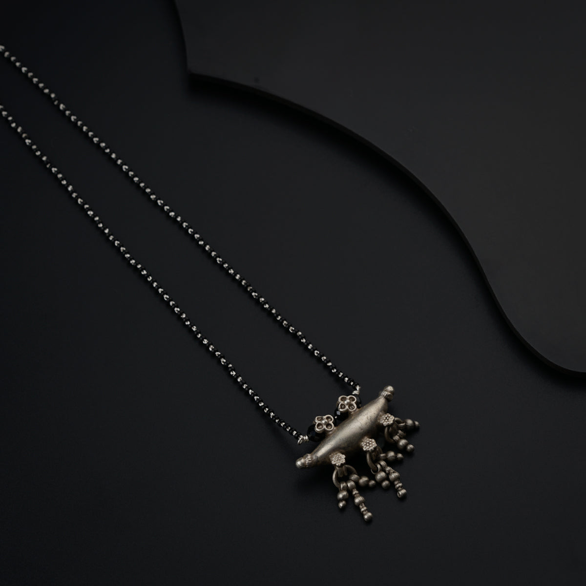 a necklace with a snowflake on it on a black surface